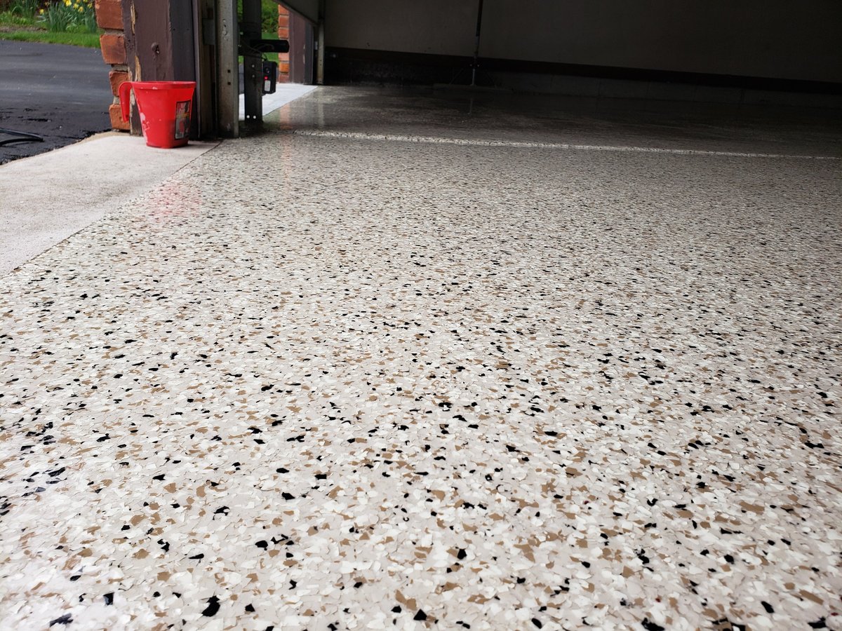 Concrete garage floor finished with a glossy epoxy and polyaspartic coating, showing the smooth protective layer and clean finished surface