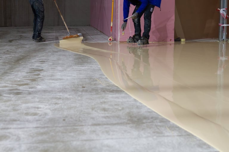 A skilled worker applying durable epoxy resin coating to a concrete floor, demonstrating the finishing techniques used for garage and concrete coatings