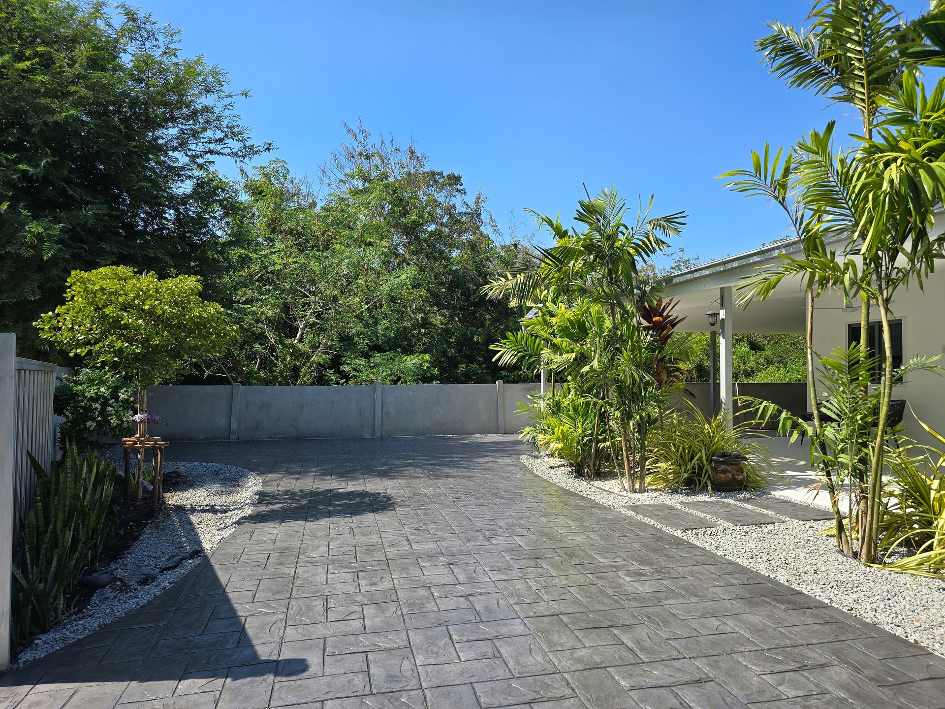 Stamped concrete driveway with intricate designs and lush landscaping