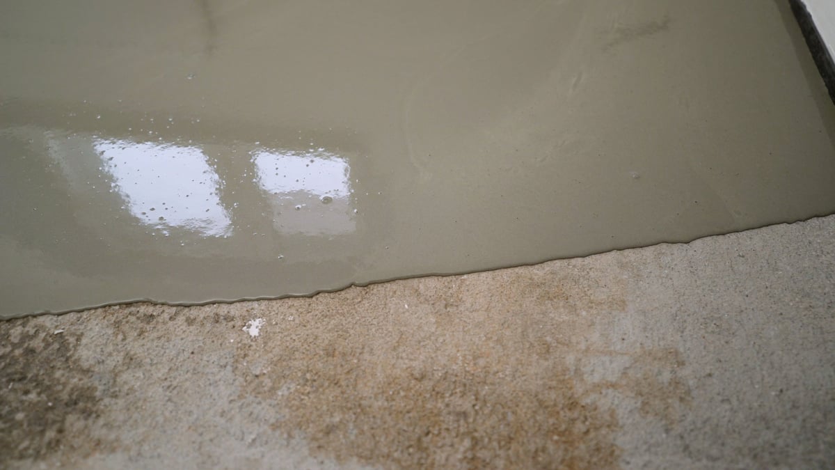 A professional applying epoxy resin coating to a concrete floor surface with a roller, creating a smooth durable finish ideal for industrial and commercial settings