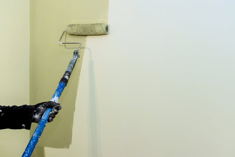 Carpenter painting wall with roller in bright living area