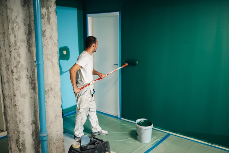 Professional painter applying green paint on wall