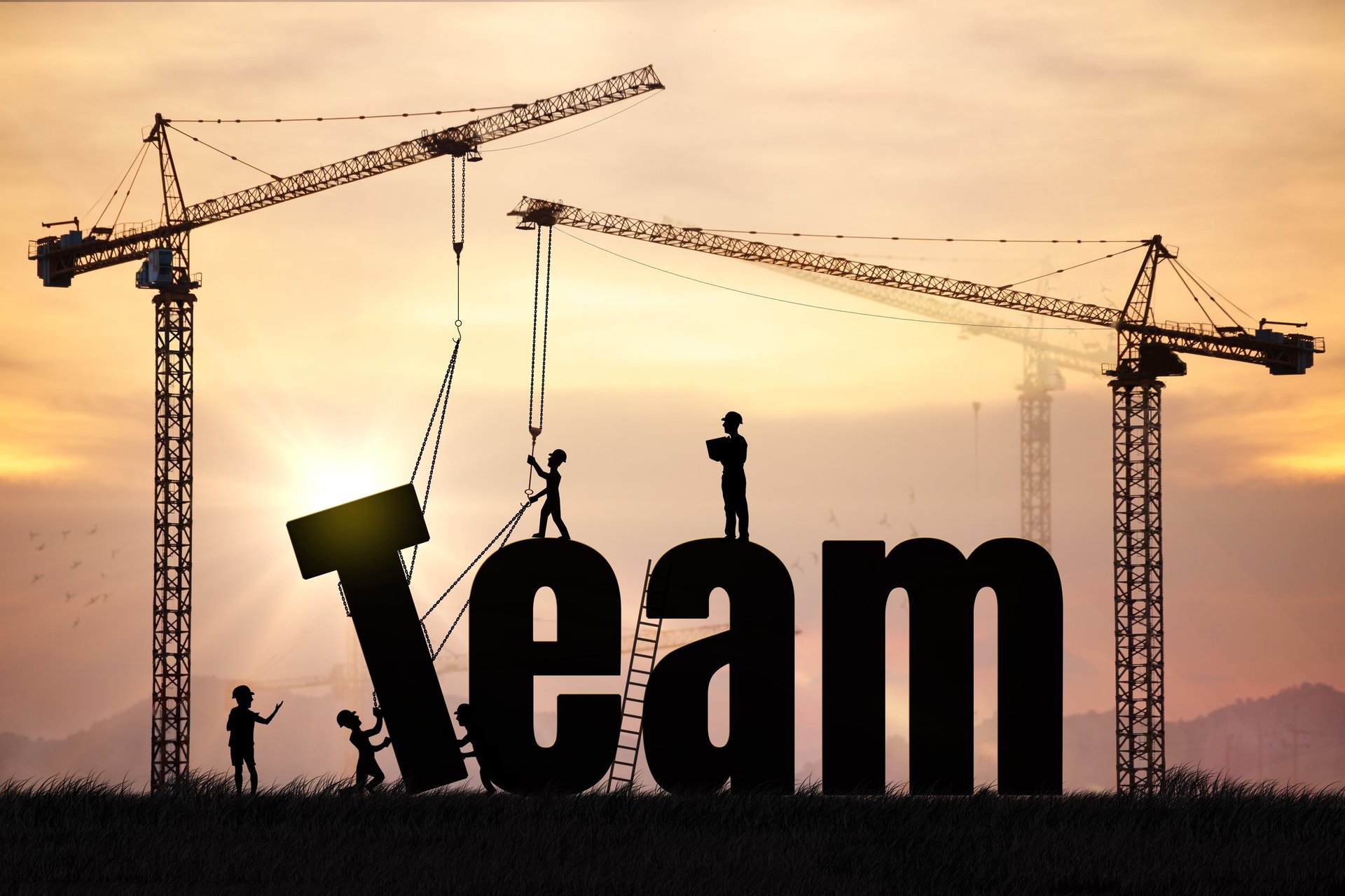 Team silhouettes representing collaboration and teamwork during sunrise