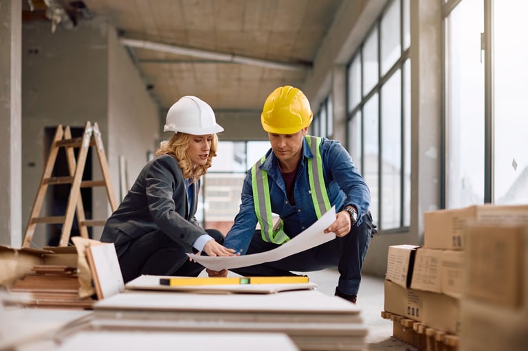 Construction worker and developer examining plans at building site