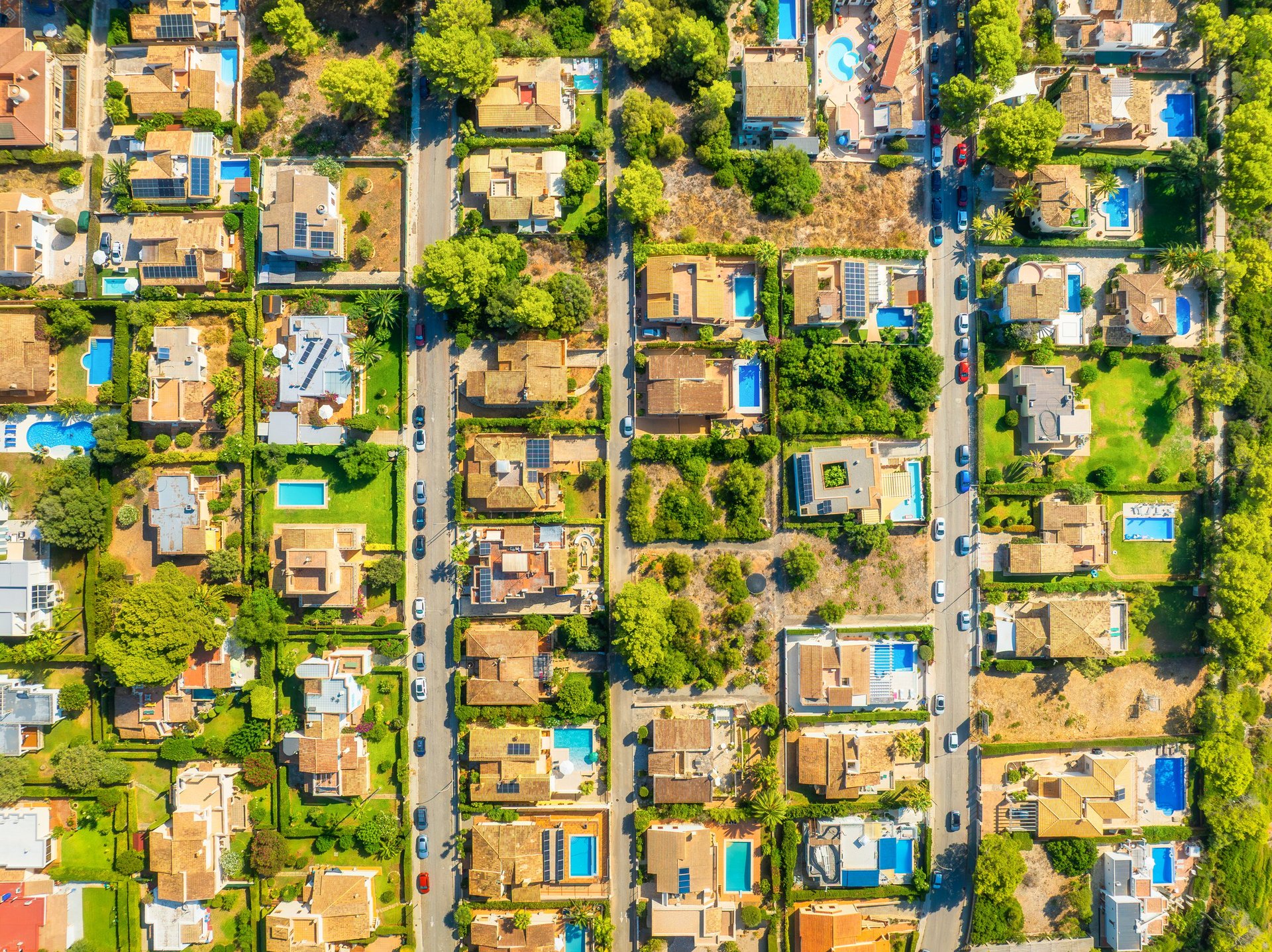 Aerial drone view of a modern residential neighborhood with houses, private swimming pools and people relaxing outdoors
