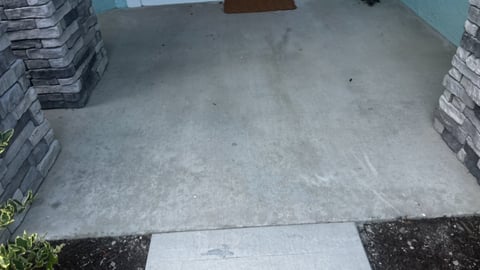 Concrete driveway or patio floor with stacked concrete pavers on sides and green building wall in background