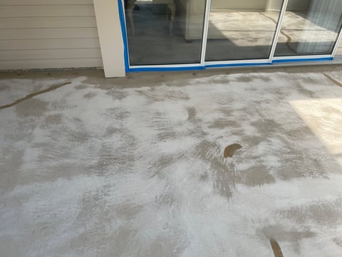 Concrete floor with water stains and marks in front of storefront with blue trim window