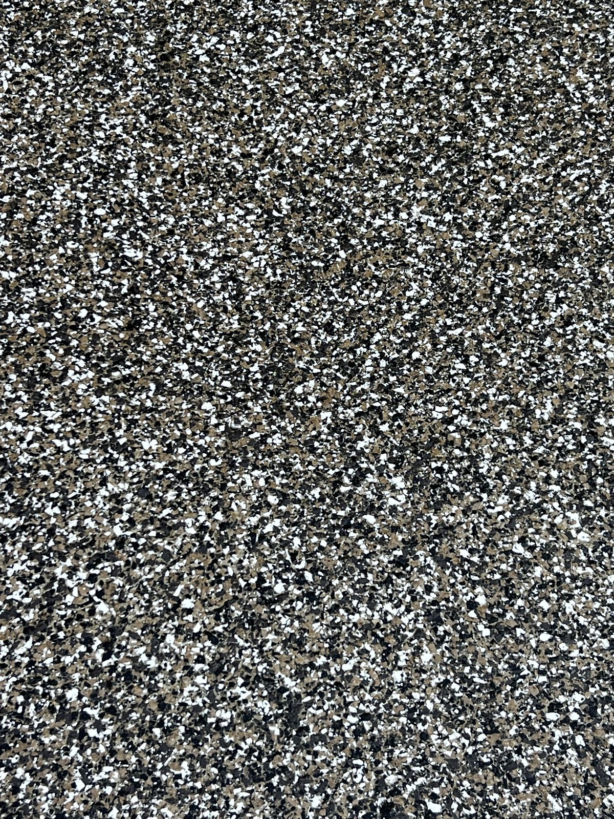 Close-up of dark asphalt surface with white aggregate stones and specks