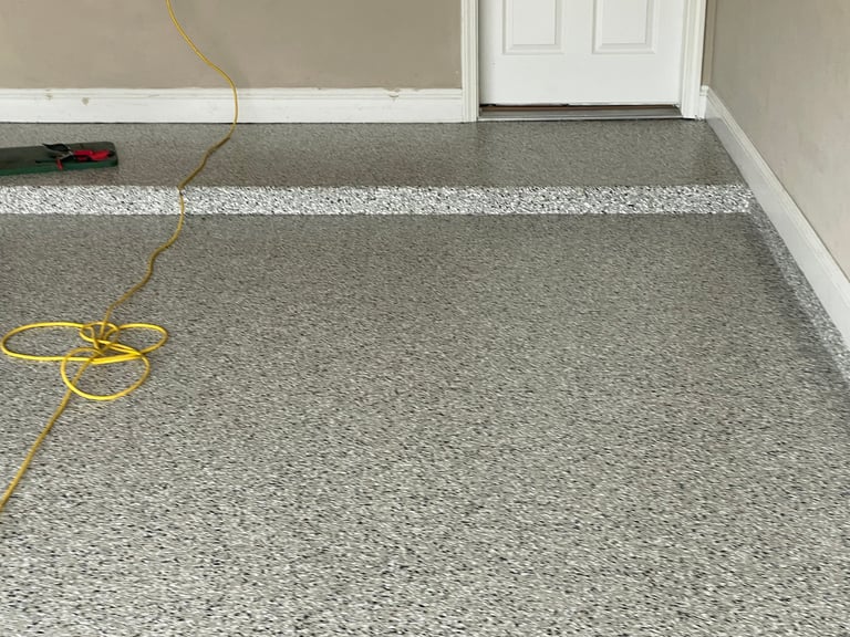 Epoxy garage floor with white stripe and yellow extension cord, white trim at doorway